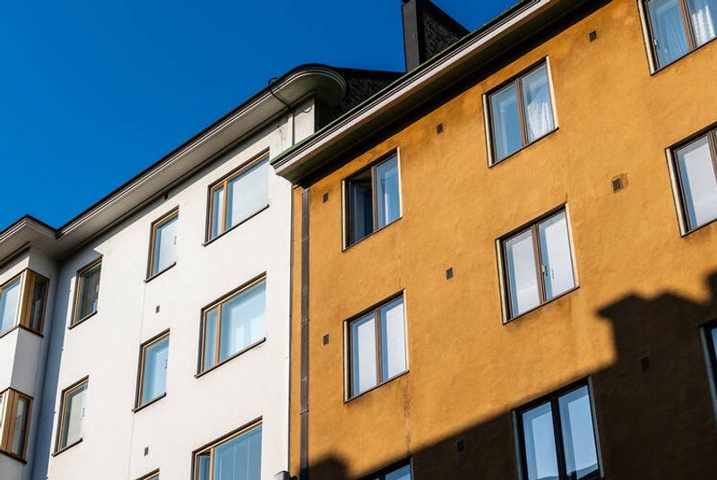 Kaksi vierekkäistä kerrostaloa, valkoinen ja ruskea. 