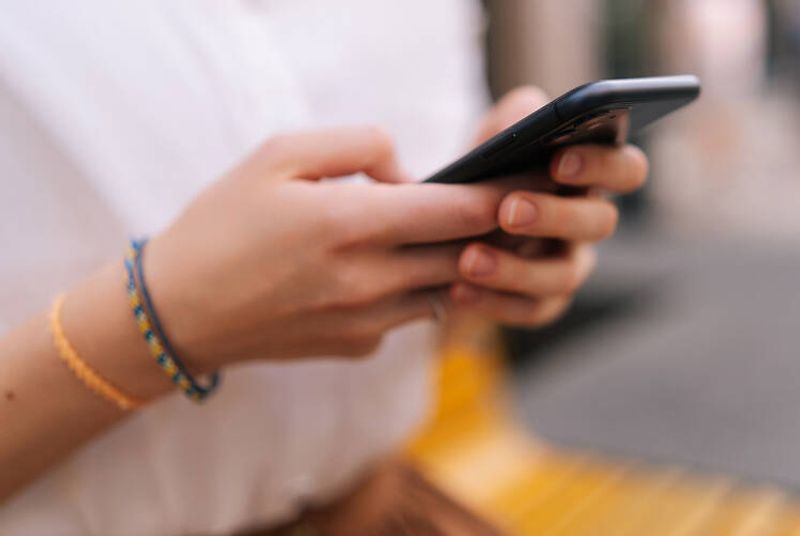 Valokuvassa on lähikuva älypuhelimesta henkilön käsissä, tausta on sumea.