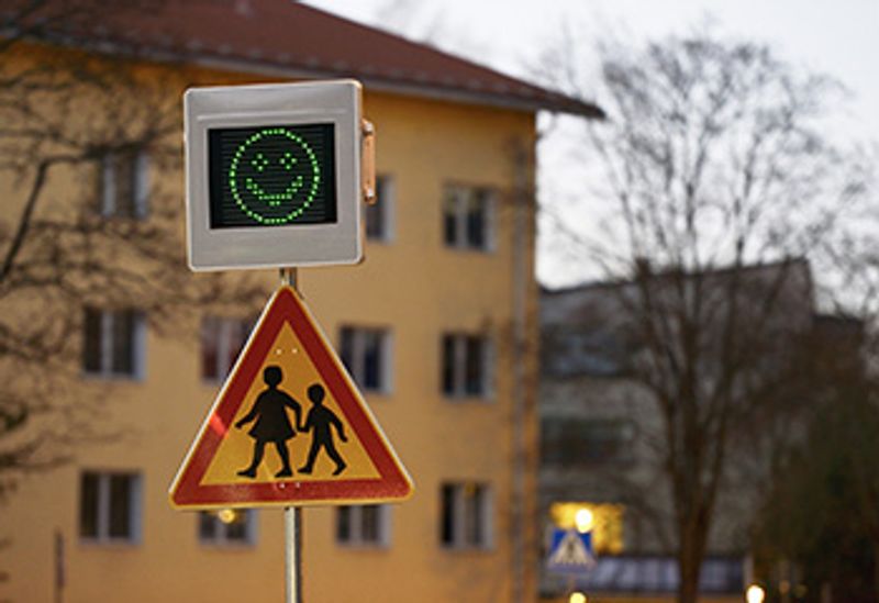 
Bilden visar en trafikskylt som varnar för barn och ett gult flerbostadshus.