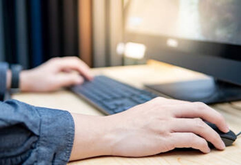 The picture shows a person's hands on a computer keyboard, with a computer screen in the background.